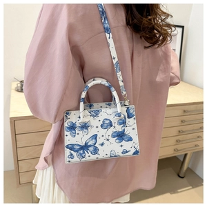 Détail du sac cabas imprimé papillon en cuir blanc avec motifs célestes bleus élégants