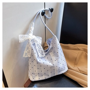 Close-up of light blue polka dot tote bag with lace stripes and a large white bow