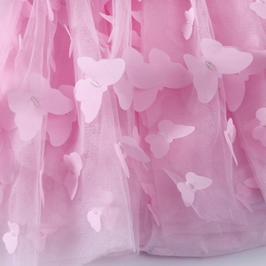 Macro detail of baby dress featuring pink mesh fabric and 3D butterfly floral appliqués