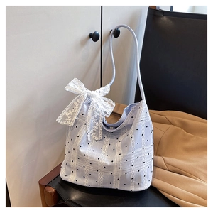 Detail of light blue bucket bag with black polka dots and a white lace bow decoration