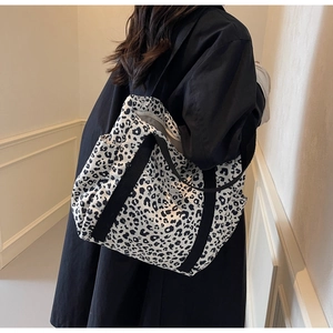Détail du sac cabas léopard avec larges anses et poches latérales sur modèle