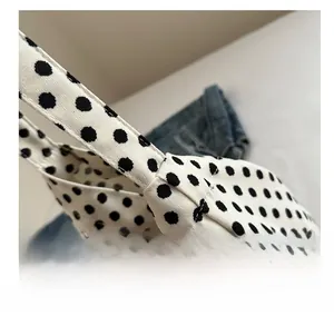 Close-up of sturdy stitching and shoulder strap attachment on white polka dot canvas tote