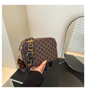 Close-up of vintage brown monogram camera bag with wide black strap and gold zippers