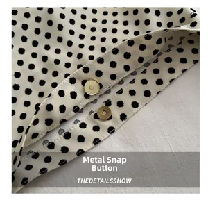 Detailed macro shot of golden magnetic buckles on polka dot patterned woven fabric bag
