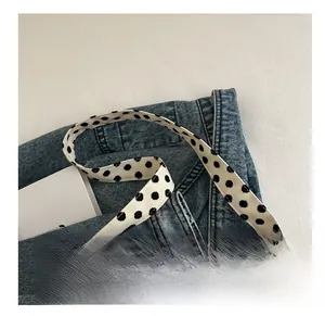 Close-up of the comfortable fabric shoulder strap on the white polka dot tote bag