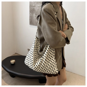 Side view of a large cream canvas tote bag with black polka dots on a female model