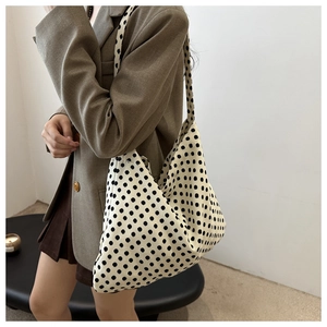 Detail of minimalist cream canvas tote with black polka dots shown in a lifestyle setting
