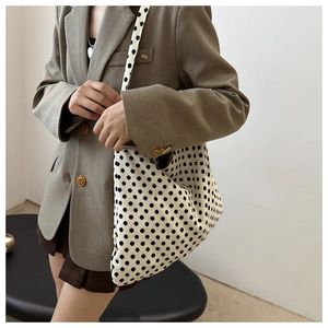Detail view of large white tote bag with black polka dots and slim shoulder straps