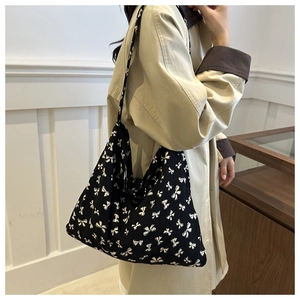 Detail of black tote bag with white bow pattern and textured corduroy material