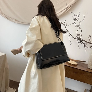 Sac fourre-tout minimaliste en cuir verni noir avec bandoulière chaîne par mannequin