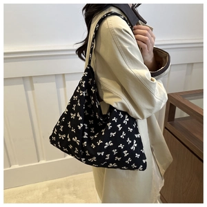 Detail view of large black canvas tote bag with white bow print for daily commuting