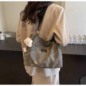 Close-up of charcoal grey canvas tote bag with leather logo patch and cloud pendant
