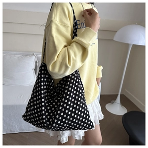 Detailed view of large capacity black and white polka dot knit tote bag on model shoulder