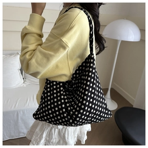 Close-up of a large black knitted tote bag with white polka dots for daily commuting