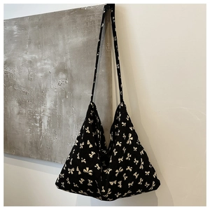Close-up of black canvas tote bag featuring white bow patterns and soft fabric texture