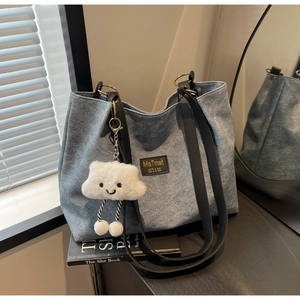 Detail of blue denim tote bag featuring leather logo patch and plush cloud charm