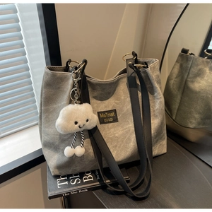 Detail of grey canvas tote bag with black leather straps and a cute cloud charm accessory