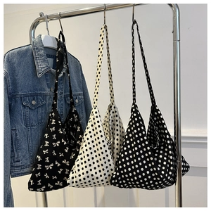 Detailed display of large canvas tote bags with polka dot and bow patterns hanging on a rack