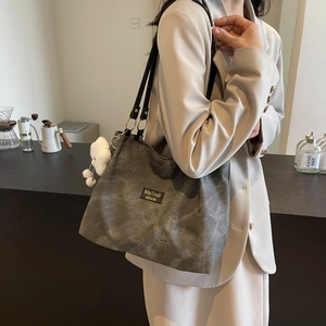 Minimalist large charcoal grey tote bag with bear charm worn on shoulder