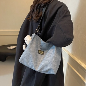 Minimalist grey textured tote bag with black wide strap and cloud pendant for daily use