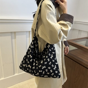Women's black canvas tote bag with white bow pattern shown on model for daily casual wear