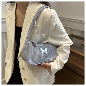 Detail of silver butterfly buckle on blue crinkled underarm bag worn by a model