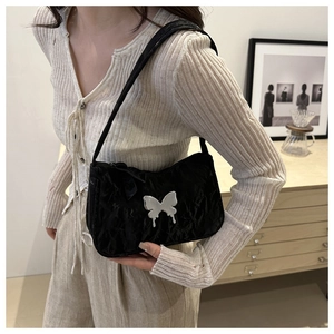 Detailed close-up of a black pleated shoulder bag with a silver butterfly charm accessory