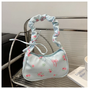 Detail van lichtblauwe handtas met rozenprints en geplooid handvat in wolkenstijl