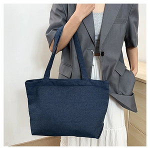 Minimalist large denim tote bag shown with shoulder strap on a model for daily use