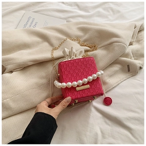 Detail of fuchsia textured bucket bag with pearl handle, gold chain and metal rivets