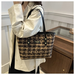 Brown checkered tote bag with black heart prints worn by a model in a home setting