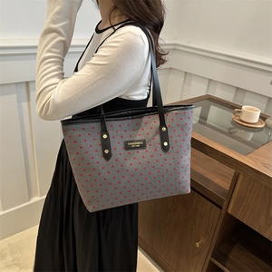 Chic grey tote bag with red heart pattern and black leather handles for daily commute