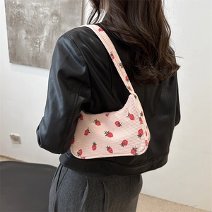 Sac baguette en velours côtelé rose à motif fraises porté par une mannequin
