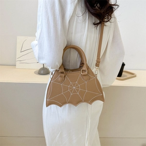 Khaki spider web wing saddle bag with stitching detail worn with elegant white dress