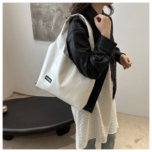 Detail view of large white oil wax leather tote bag worn on shoulder by a model