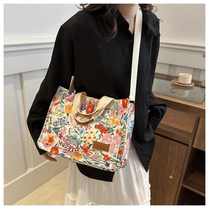 Close-up of floral oxford tote with brown leather label and adjustable wide shoulder strap