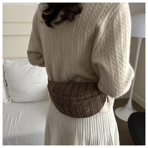 Close-up of brown striped canvas waist bag on a model wearing a cozy knit sweater