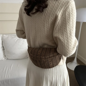 Brown striped moon-shaped crossbody chest bag for women in a minimalist home setting