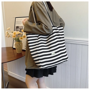 Detail of a large capacity striped tote bag with a handmade label in a home setting