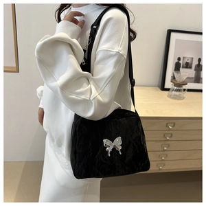 Detail of black pleated shoulder bag featuring a liquid silver butterfly logo on a wide strap