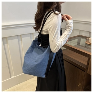 Vue latérale d'un grand sac seau en jean porté par un mannequin dans un intérieur lumineux