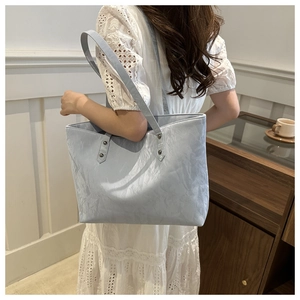 Detail of light blue tote bag with unique wrinkled texture and thin leather shoulder strap