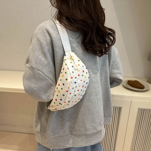 Bolso de pecho de lona con lunares de colores y correa ajustable llevado por modelo
