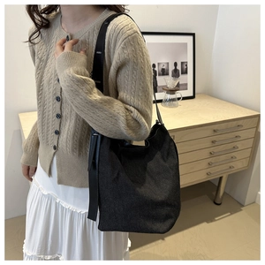Sac seau noir en denim avec bandoulière réglable dans un décor domestique épuré