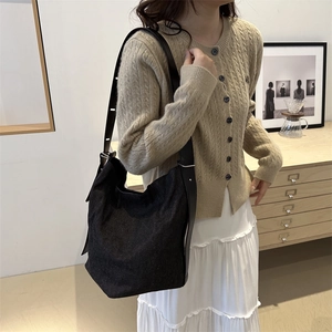 Sac seau en toile denim noire avec large bandoulière porté sur un pull en maille