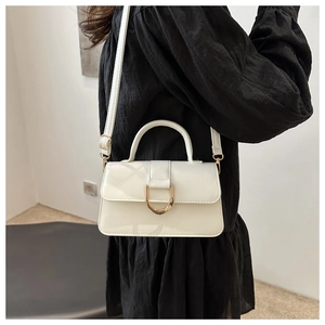 White rectangular handbag with large gold D-buckle shown on model with black dress