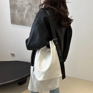 Sac seau minimaliste en toile blanche avec large bandoulière porté par un mannequin