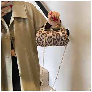 Close-up of leopard print handbag featuring a gold metal handle and a jeweled clasp