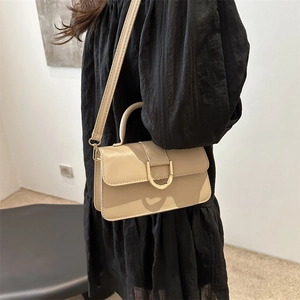 Minimalist beige leather handbag with gold horseshoe buckle and adjustable strap