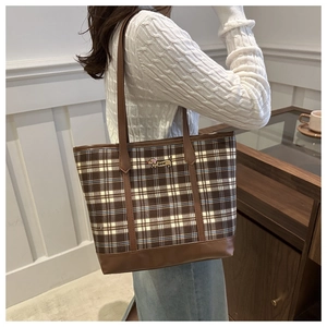 Detailed shot of brown checkered tote bag with embroidered dachshund on white sweater